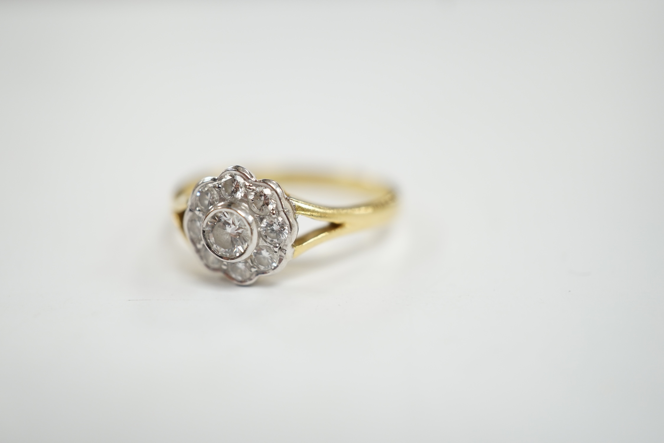 A modern 18ct gold and nine stone diamond set flower head cluster ring, size M, gross weight 3 grams.